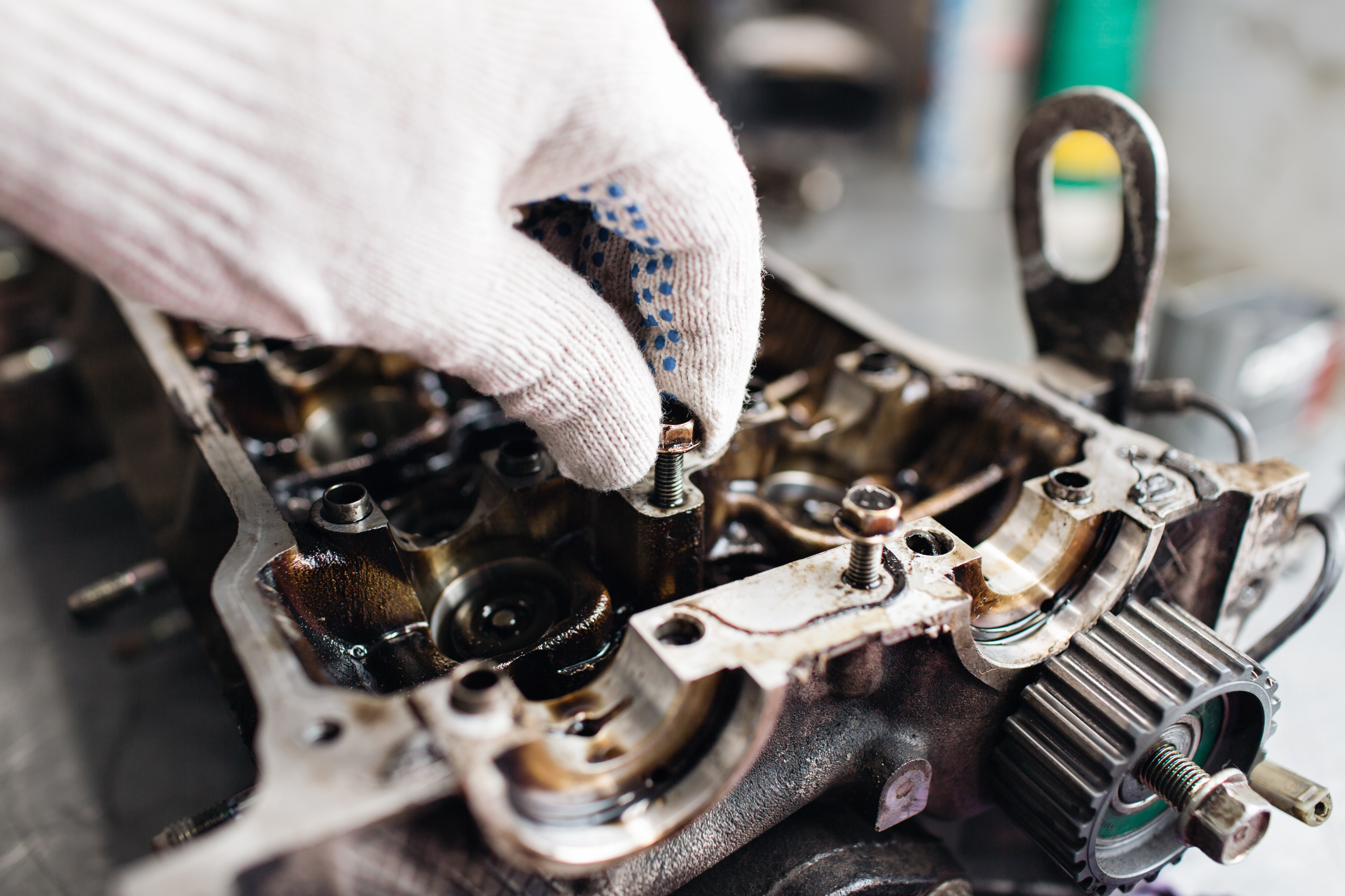 a hand putting a bolt into a car motor head